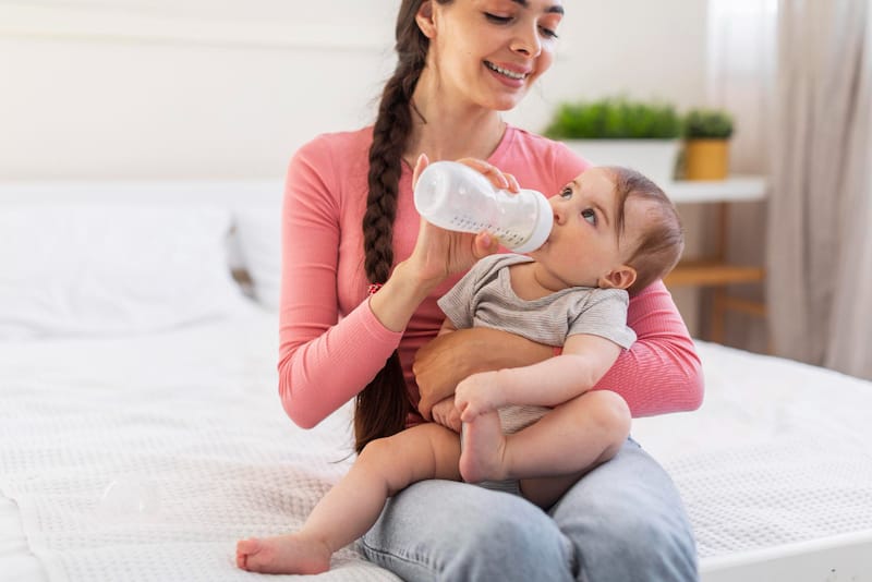 Mom is bottle feeding whole milk to her toddler son