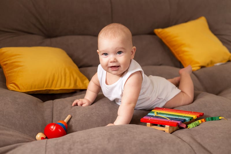 An infant boy is on the sofa practicing tummy time