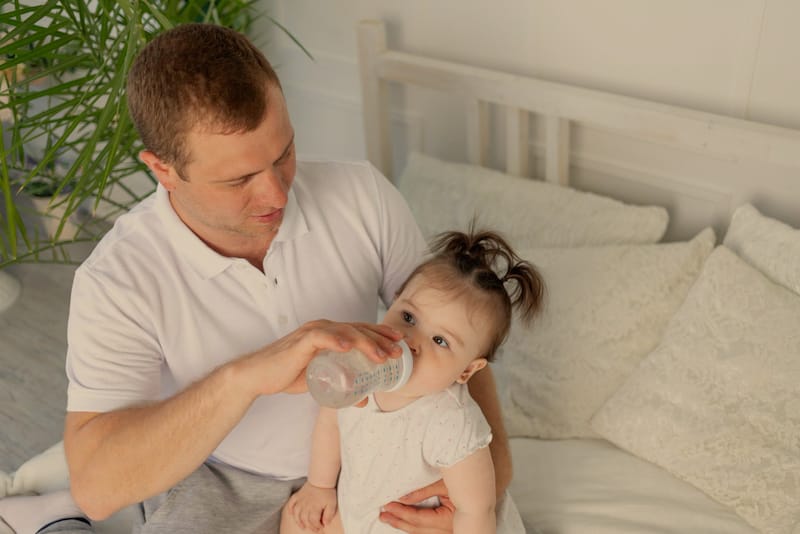 Dad is bottle feeding water to his infant baby girl