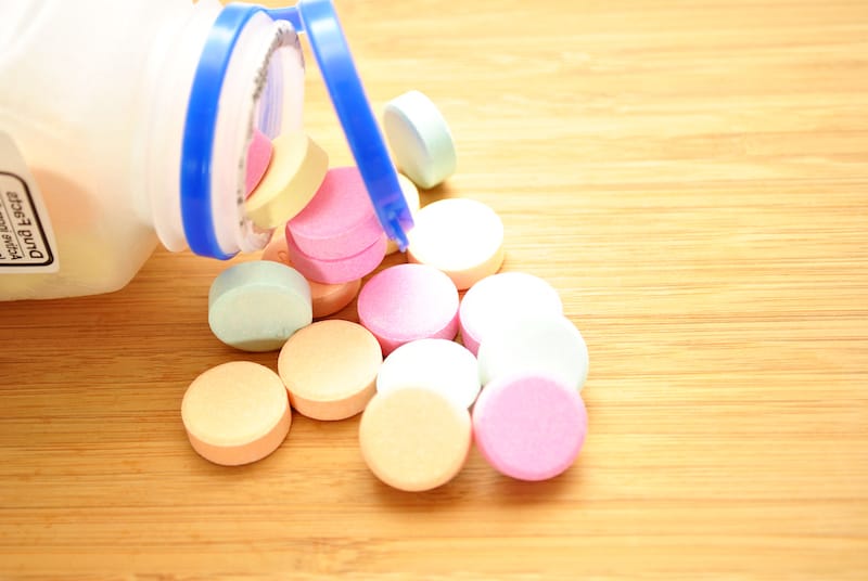 A container of antacid is open, showing the various colored antacid chewable pills.