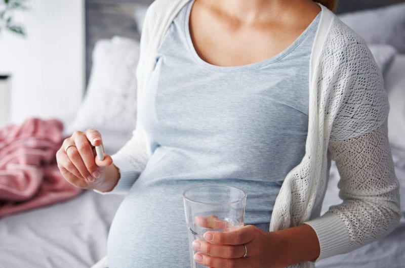 A young pregnant woman is taking iron supplements to eliminate iron deficiency during her pregnancy.