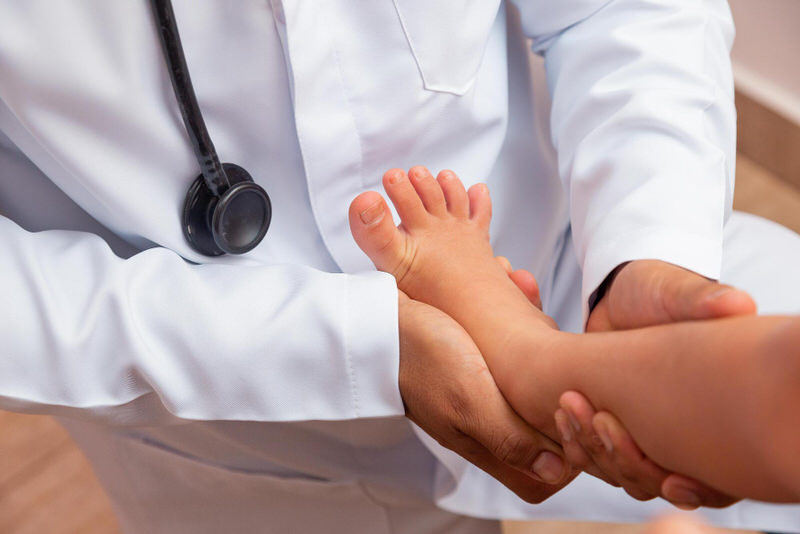 A foot doctor is checking a toddler patient on treatment options for her Intoeing condition