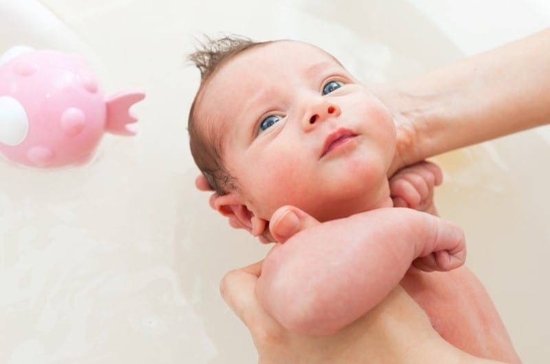 Bathing newborn in a sink full of water.