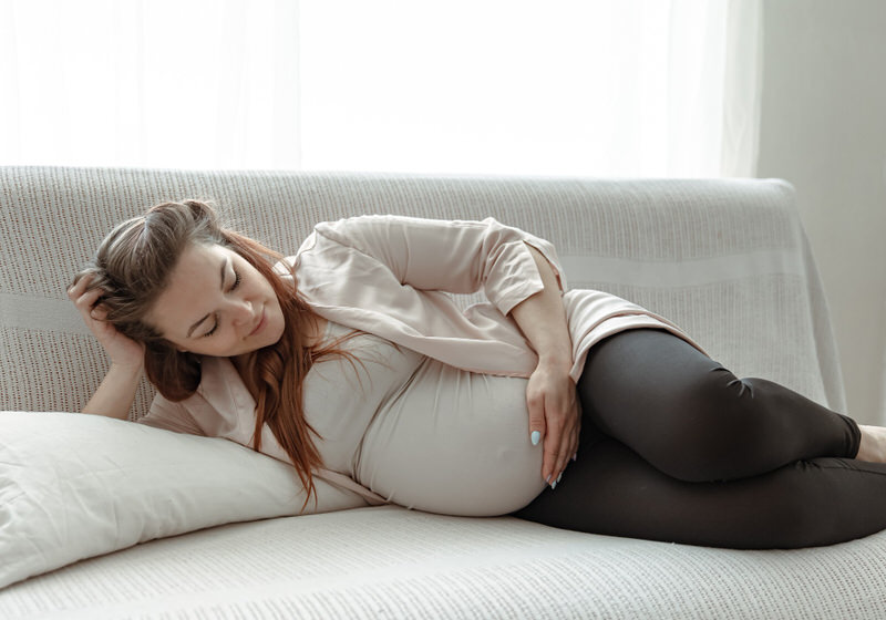 A pregnant woman is laying on her side examining her pregnant belly