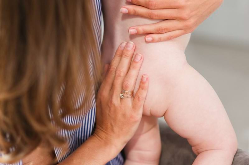 A mother checks her baby's bum and back for any sign of baby acne.