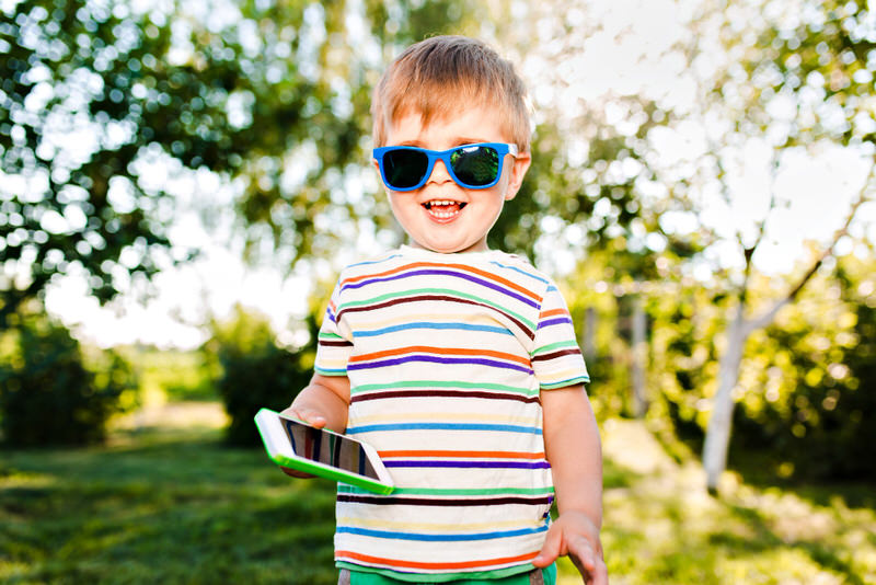A toddler boy is posing for a picture while playing at the park on a sunny day