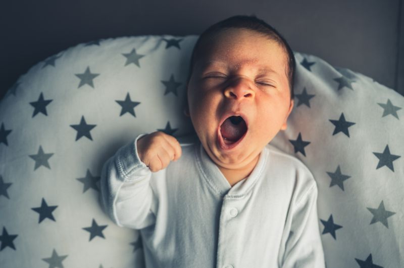 A newborn baby is yawning and is ready to sleep at night