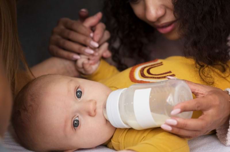 A mother is giving formula milk to her baby to supplement for breastmilk. 