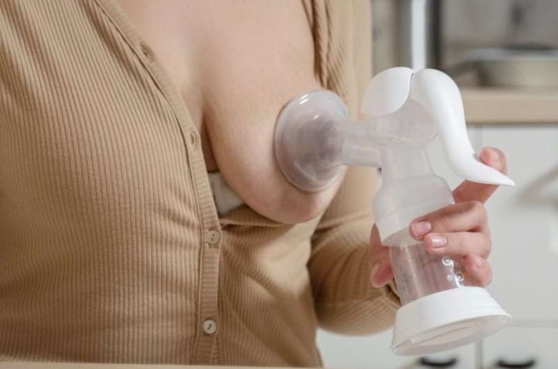 A woman is using breast pump to express her milk and store it for later use.