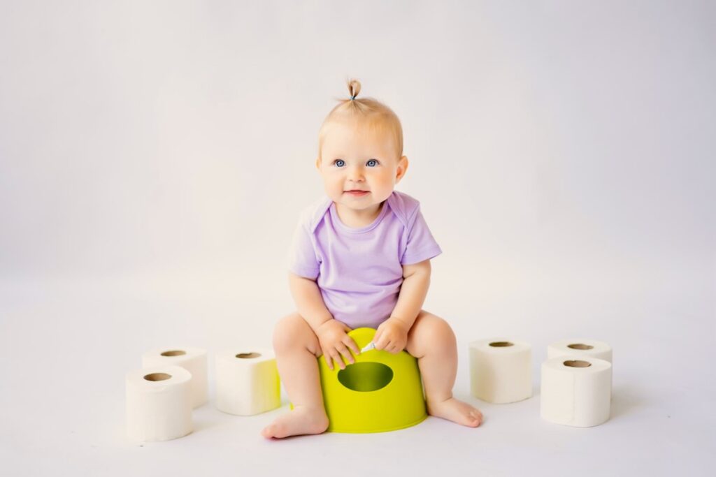 A 2 year old toddler girl is sitting on the potty as practice during potty training